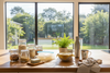Eco-friendly home products like reusable jars, beeswax wraps, and stainless steel bottles on a sunlit kitchen counter